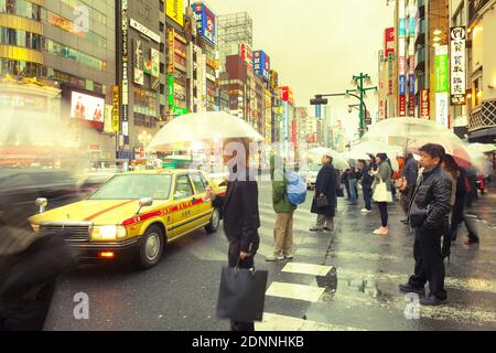 Shinjuku, Tokyo, Giappone - Persone con ombrelloni sotto la pioggia nel vivace quartiere di Shinjuku. Foto Stock