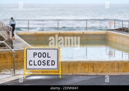 La piscina dell'oceano è in fase di rifornimento e un cartello di chiusura della piscina, dopo la pulizia da parte del volontario locale 'Dads Army' presso la Black Head Beach Ocean Pool in Australia Foto Stock