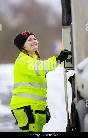 Donna che utilizza un veicolo per la raccolta rifiuti Foto Stock