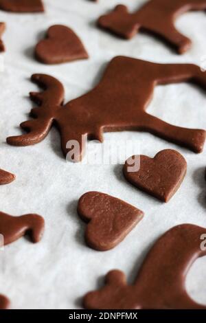 Vari biscotti di pan di zenzero su carta da forno pronta per forno. Cibo tradizionale di Natale e Capodanno. Foto Stock