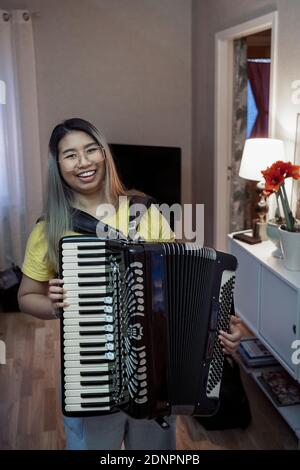 Donna sorridente che suona la fisarmonica Foto Stock