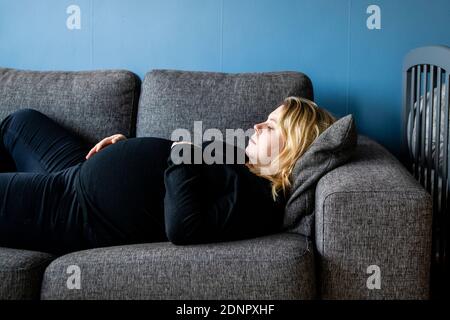 Donna incinta sdraiato sul divano Foto Stock