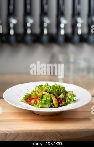 Insalata di peperone gialla e rossa arrosto con capperi e olive in una ciotola blu. Concetto di cibo sano su sfondo di legno. Spazio di copia. Vegetab alla griglia Foto Stock