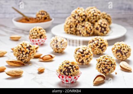 Primo piano sui tartufi francesi al cioccolato fondente ricoperti di mandorle tritate, serviti su uno sfondo in marmo bianco, vista dall'alto Foto Stock