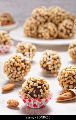 Primo piano sui tartufi francesi al cioccolato fondente ricoperti di mandorle tritate, serviti su uno sfondo in marmo bianco, vista dall'alto Foto Stock