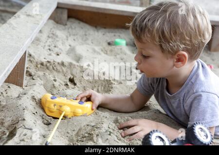 Capretto che gioca con i giocattoli in un sandbox Foto Stock