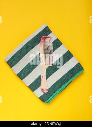 Accessori da bagno su sfondo giallo. Asciugamano, spazzola per capelli. Cura dei capelli. Vista dall'alto. Foto Stock