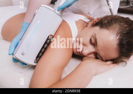 Primo piano di una bella donna matura che rilassa una clinica di bellezza, ottenendo la terapia delle endosfere sulle sue braccia. Donna che riceve un trattamento dimagrante per tutto il corpo Foto Stock