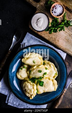 Gnocchi di patata di vernice Ucraina con guarnitura di erba cipollina e panna acida Foto Stock