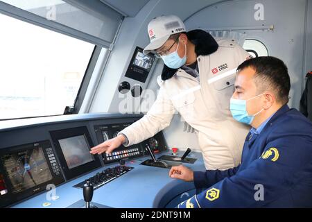 Tashkent, Uzbekistan. 17 Dicembre 2020. Un tecnico cinese mostra l'operazione al conducente uzbeko sulla locomotiva elettrica a Tashkent, Uzbekistan, 17 dicembre 2020. Giovedì l'Uzbekistan ha ricevuto la prima serie di quattro locomotive elettriche per impieghi gravosi e rispettose dell'ambiente dai suoi fornitori cinesi. L'Uzbekistan riceverà un totale di 30 locomotive elettriche dalla Cina, progettate sia per il trasporto di passeggeri che di merci, di cui 24 in base a un contratto del valore di 134 milioni di dollari USA firmato nel 2019 e altri sei acquistati all'inizio di quest'anno. Credit: Zafar Khalilov/Xinhua/Alamy Live News Foto Stock