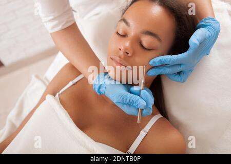 Giovane donna africana che ha i blackheads rimossi dal cosmetologist professionale Foto Stock