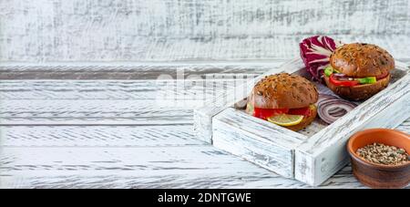 panino a grani interi farcito con insalata, salmone, avocado e pomodori - colazione a grani interi appena sfornata. Banner. Foto Stock
