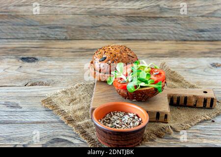 Hamburger vegani con insalata di mais e pomodoro su sfondo di legno. Concetto di cibo basato su piante Foto Stock