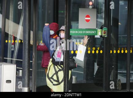 Estinzione ribellione attivisti ambientali finzione le mani con super colla sul vetro della porta durante la protesta blocca l'accesso dei terminali dell'aeroporto di Schiphol Amsterdam in mezzo alla pandemia di coronavirus il 18 dicembre 2020 ad Amsterdam, Paesi Bassi. I manifestanti ambientali della ribellione per l'estinzione fanno una dimostrazione contro il governo e la posizione eccezionale dell'aviazione dello Schiphol, si risparmiano le misure di blocco, si consente di superare le norme sull'azoto, non è necessario richiedere permessi ambientali; e può continuare a crescere sono nel bel mezzo di una crisi climatica. Kerosen Foto Stock