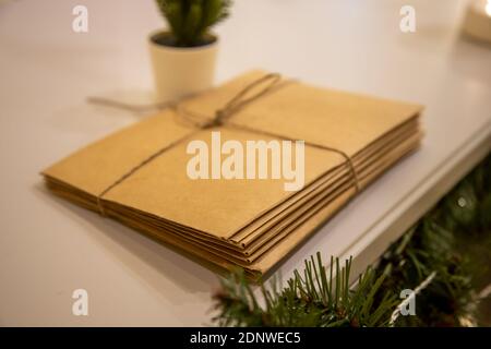 Un mazzo di lettere a Babbo Natale fatto di artigianato La carta legata con una corda si trova accanto alle decorazioni natalizie E un albero di Natale Foto Stock