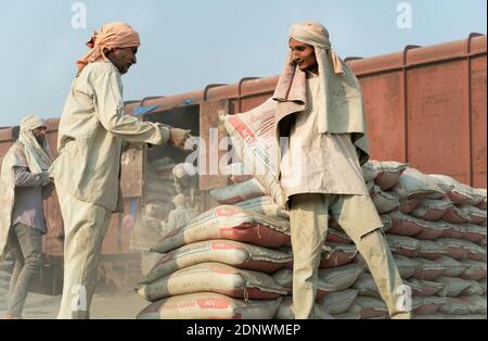 Uomo che indossa solo sciarpa per la testa come protezione impiegata per spostare sacchi di cemento da treno a camion a Mathura, Uttar Pradesh, India. Foto Stock