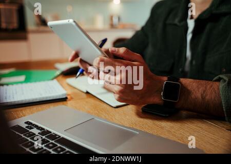 Uomo d'affari da corsa misto che lavora su tablet digitale mentre si siede ufficio domestico che completa le offerte di affari Foto Stock