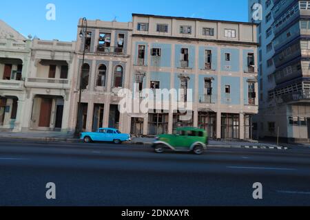 Auto d'epoca americane alomg il Malecon, dietro è il Castello Morro, una pittoresca fortezza che protegge l'ingresso alla baia di l'Avana Foto Stock