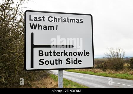 Wham, Contea di Durham 18 dicembre 2020. Il tempo può essere opaco e la contea di Durham può dover rimanere nel livello 3, ma non ha ammalato l'umorismo di almeno una persona. Questo cartello stradale ha guadagnato un po 'di allegria di Natale quando qualcuno ha aggiunto ufficiosamente il titolo della canzone: "Ultimo Natale" a un cartello che indica il villaggio di Wham nella contea di Durham. Credit: David Forster/Alamy Live News Foto Stock