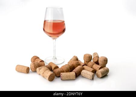 bicchiere di vino rosato con tappi sparsi usati su bianco sfondo Foto Stock