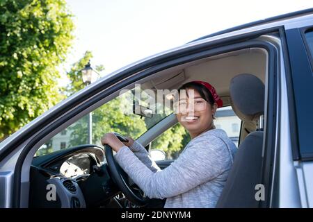 Donna sorridente seduto in auto Foto Stock