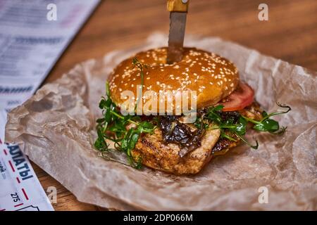 Delizioso hamburger di pollo su carta e tavola di legno Foto Stock
