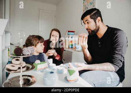 Ragazza che ha una festa del tè con i genitori Foto Stock