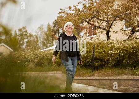 Felice donna anziana che guarda via Foto Stock