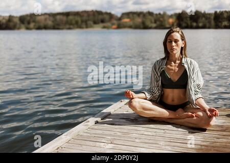 Woman meditating on jetty Stock Photo