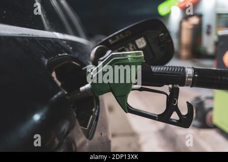 un ugello della pompa benzina è bloccato nel bocchettone di riempimento di una macchina Foto Stock