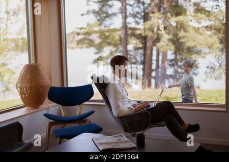 Uomo con notebook che guarda attraverso la finestra Foto Stock