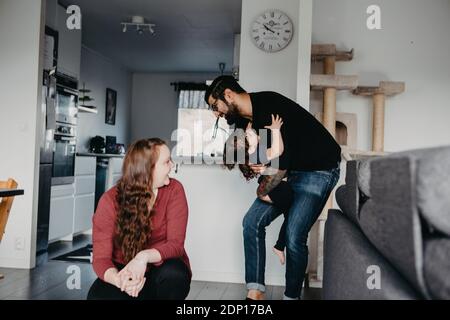Madre che guarda il padre che gioca con la figlia Foto Stock