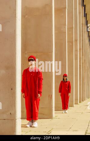 Giovane coppia che indossa tute rosse e cappelli in piedi in un riga Foto Stock