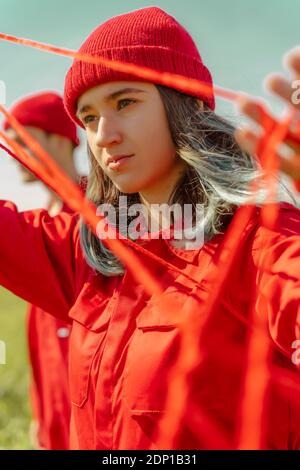 Ritratto di giovane donna vestita di rosso che si esibisce di rosso stringa all'esterno Foto Stock