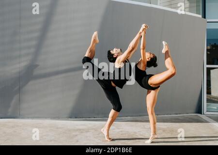 Ginnasti professionali in piedi su una gamba mentre equilibrano da grigio parete Foto Stock