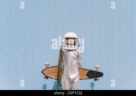 Bambino vestito come un astronauta con longboard Foto Stock