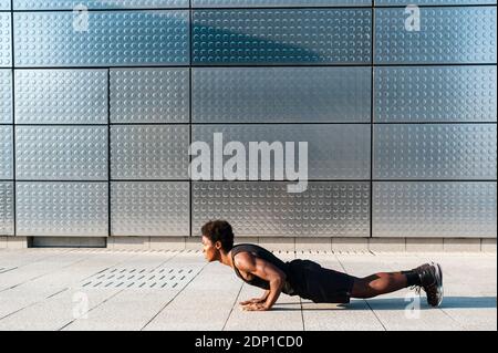 Spagna, Madrid, giovane atletico afro uomo che fa spinta in su in zona urbana, Gioventù, Etnicità, sano, Sport Foto Stock