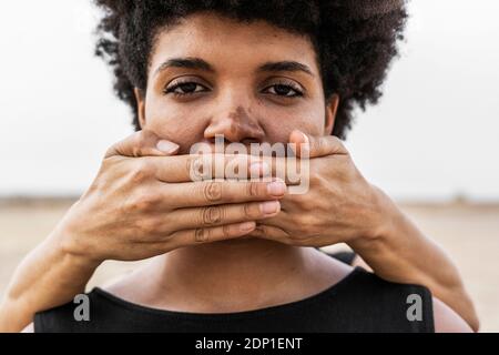 Donna con le mani in mano che copre la bocca di un'altra donna, close-up Foto Stock