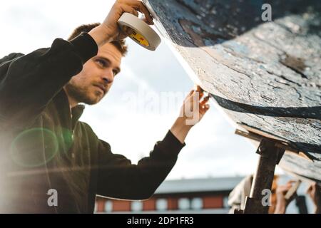 Uomo adesivo nastro di mascheratura sulla barca Foto Stock