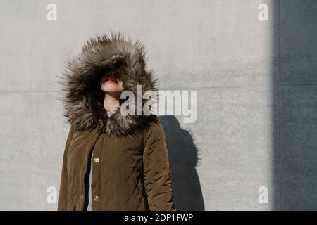 Ritratto di donna anonimo con cappotto invernale sullo sfondo di una parete Foto Stock