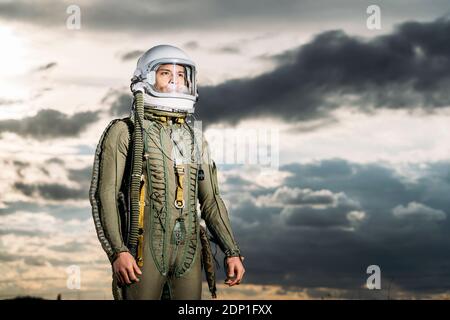 Ponendo l'uomo vestito come un astronauta con drammatica nuvole in background Foto Stock