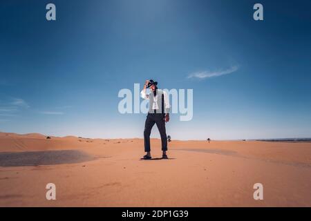 Uomo con la barba e hat nelle dune del deserto del Marocco Foto Stock