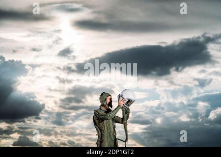 Ponendo l'uomo vestito come un astronauta con drammatica nuvole in background Foto Stock