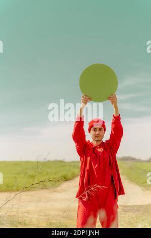 Ritratto di giovane vestito di rosso che tiene un cerchio verde Foto Stock