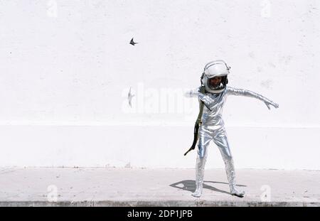 Ragazzo in costume astronauta che gioca mentre si è in piedi contro muro dentro città Foto Stock