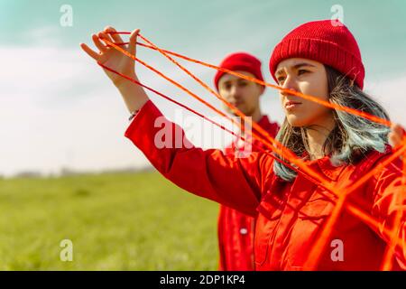 Ritratto di giovane donna vestita di rosso che si esibisce di rosso stringa all'esterno Foto Stock