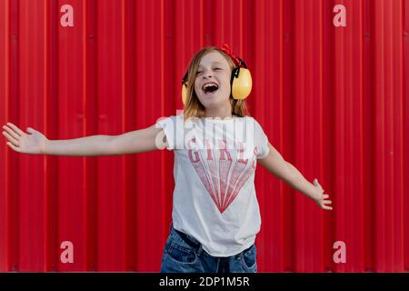 Ragazza con cuffie di protezione nella parte anteriore della parete rossa Foto Stock