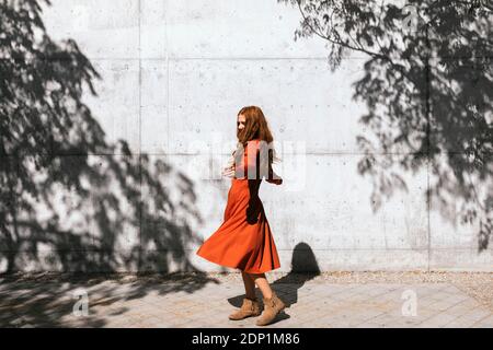 Giovane donna con le braccia allungate che gira contro la parete d'ombra dell'albero Foto Stock