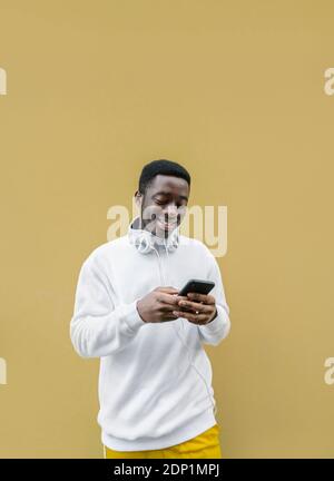 Ritratto di un giovane sorridente che guarda lo smartphone Foto Stock