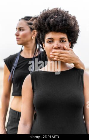 Donna di mano che copre la bocca di un'altra donna Foto Stock